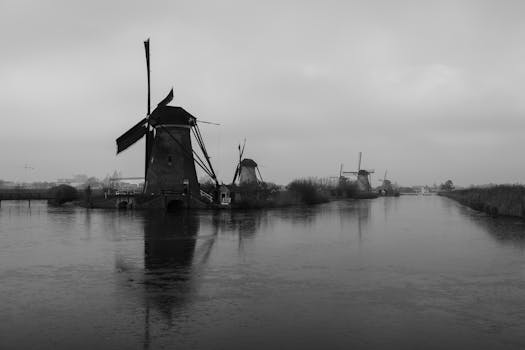 Stunning black and white photo of iconic windmills reflected in the calm waters of Kinderdijk, Holland.