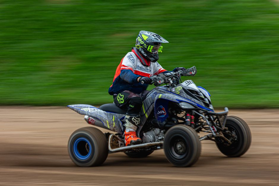 Action shot of a quad bike racer speeding on a dirt track, showcasing motion blur and speed.