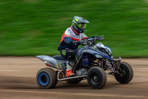 Free Action shot of a quad bike racer speeding on a dirt track, showcasing motion blur and speed. Stock Photo