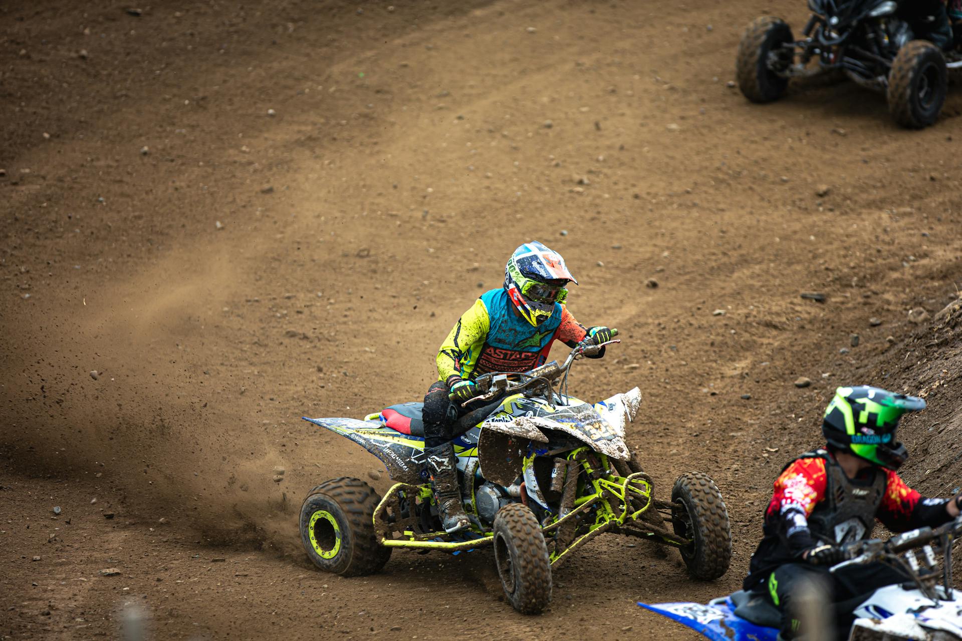 Action-packed image of quad bike racers speeding on a dirt track, showcasing intense competition and skill.