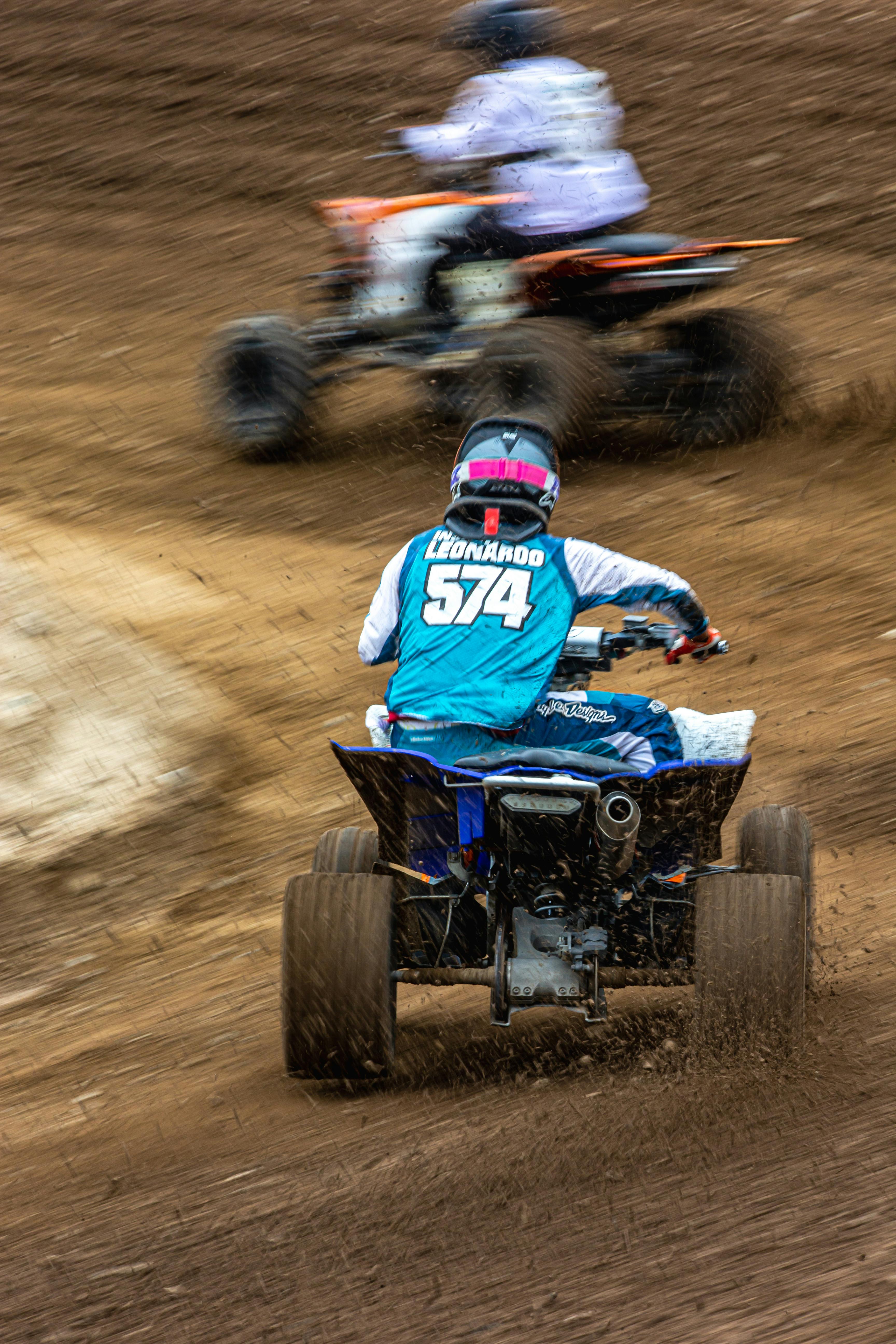 Action-packed quad bike racing on a mud track with riders in focus.