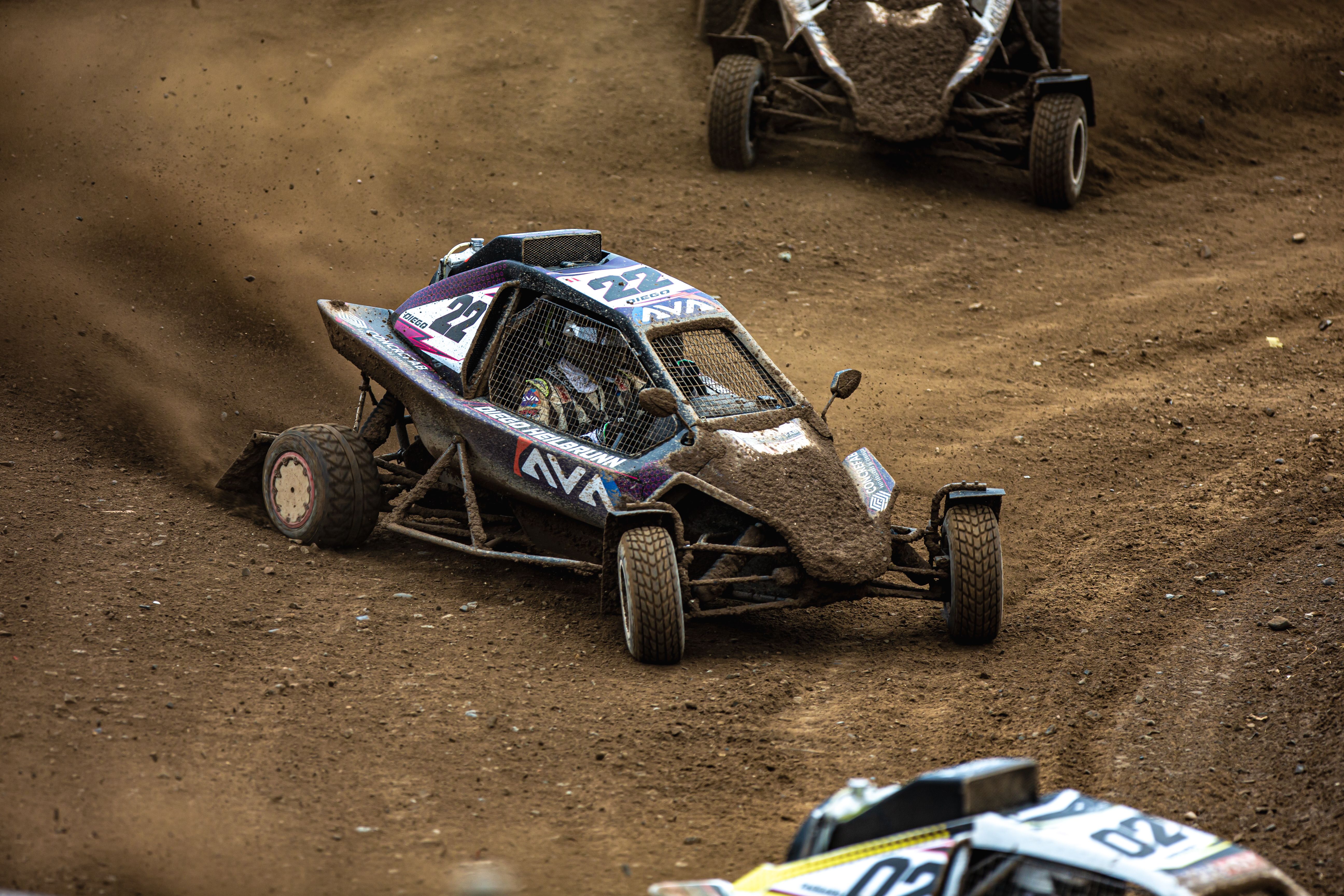 Close-up action of offroad buggy racing on a muddy track, showcasing thrilling motorsport competition.