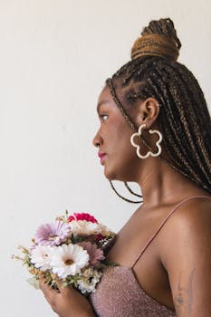 Portrait of a woman with braided hair holding flowers against a white background. Studio shoot.