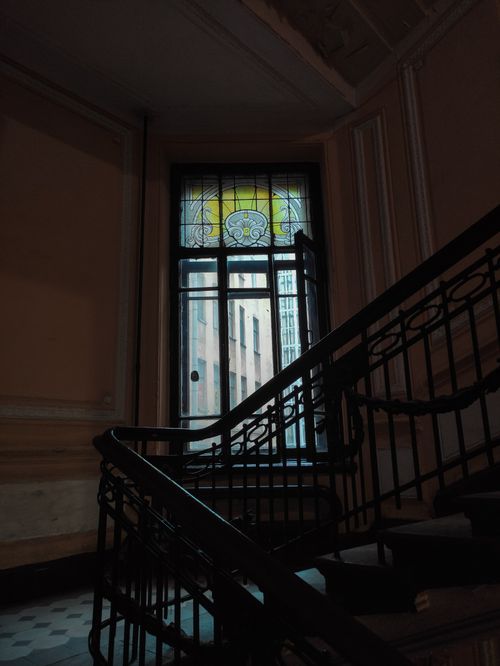 Free A vintage staircase with ornate iron railings and a stained glass window. Stock Photo