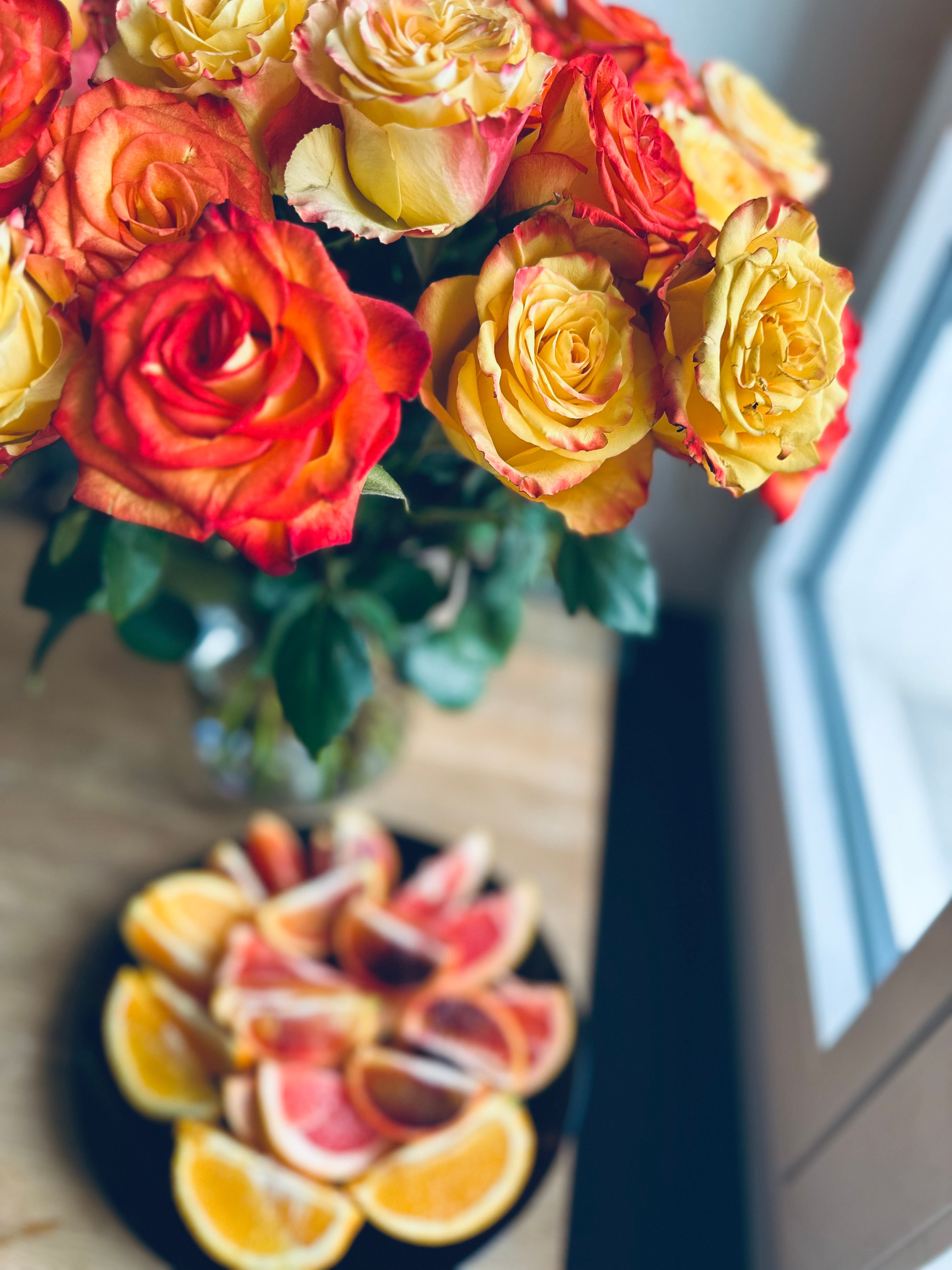 A colourful flower arrangement rests on a wooden table in natural light.