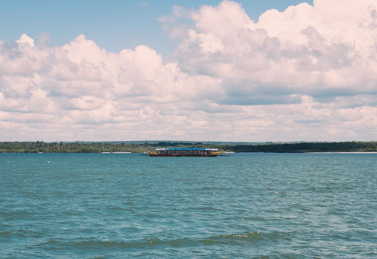 a serene view of a boat sailing on the ocean with fluffy clouds above
