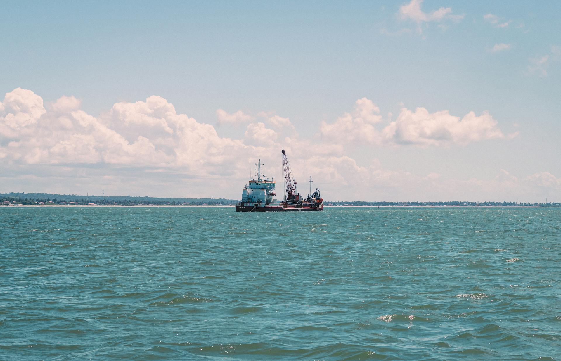 Dredger ship working offshore near João Pessoa, Brazil, under a clear sky.