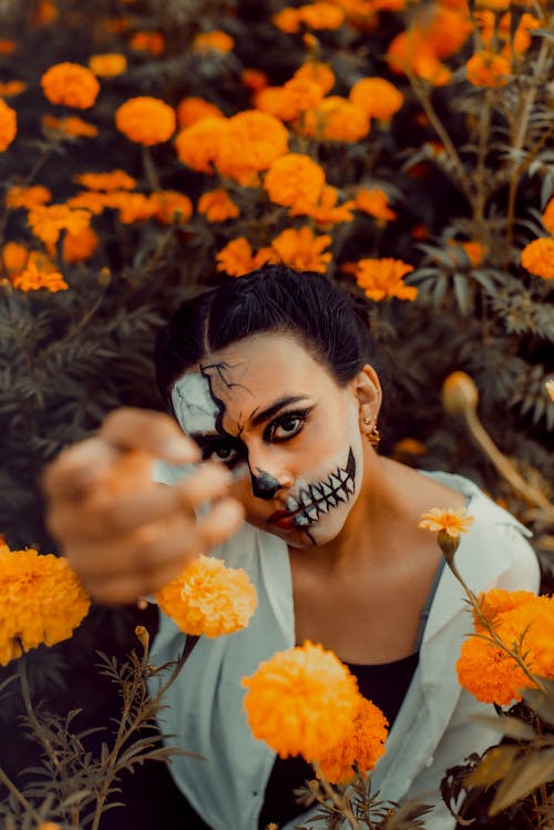 Young Woman in Stage Makeup Among Orange Flowers