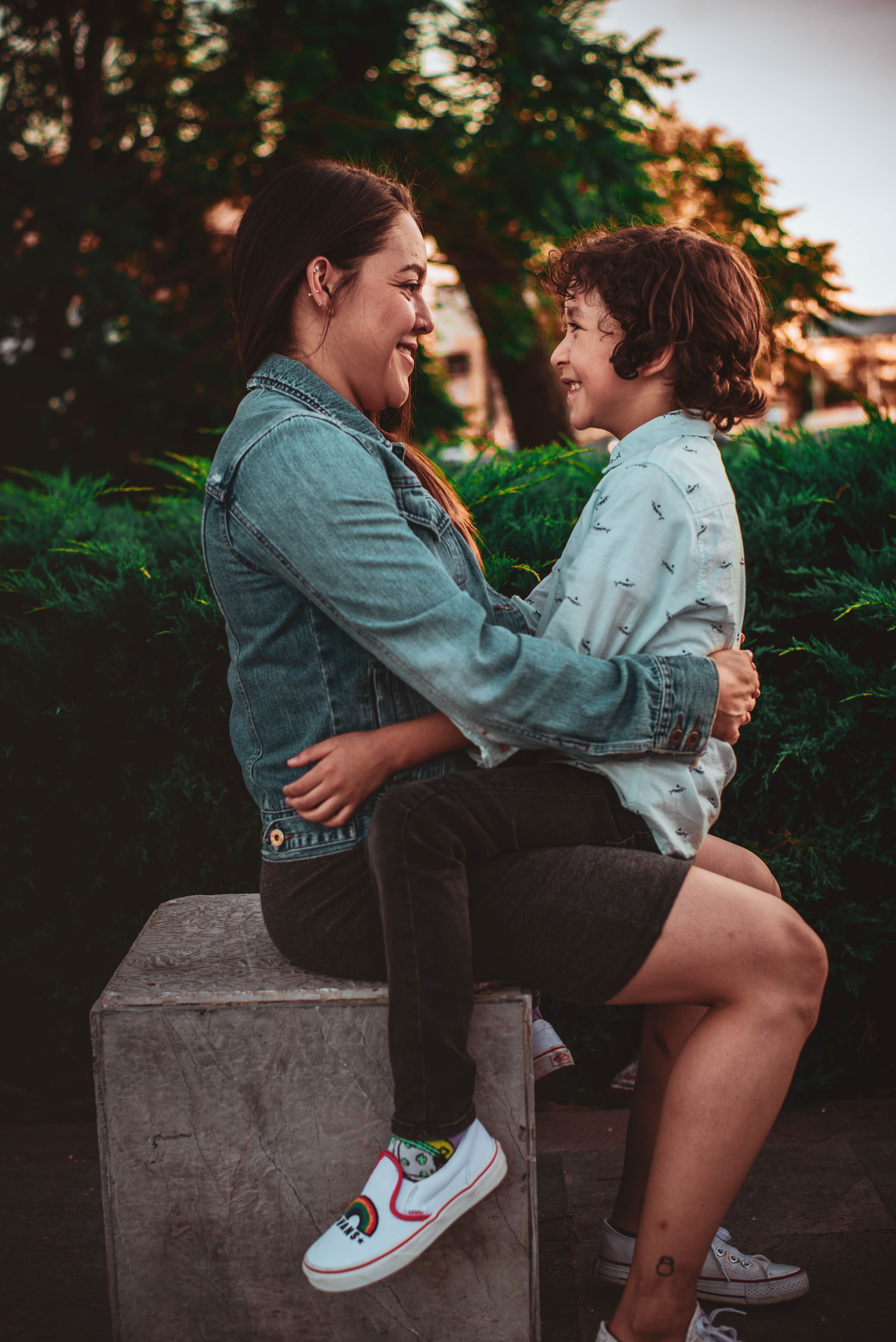 A joyful outdoor scene of a mother embracing her son with warm smiles.