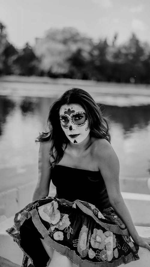Portrait of a Young Woman Wearing Face Paint Sitting on a Lakeshore