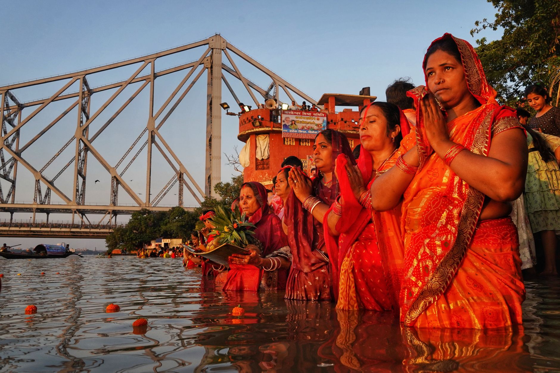 Women in traditional attire praying in the Ganges River by Howrah Bridge, Kolkata.