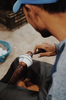 A skilled artisan handcrafts a cricket ball in Meerut, India, showcasing traditional techniques.