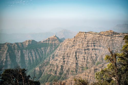 Free Breathtaking landscape of a mountain range with rocky cliffs and mist under a clear blue sky. Stock Photo