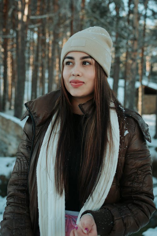 A woman in a winter jacket and beanie standing in the snow
