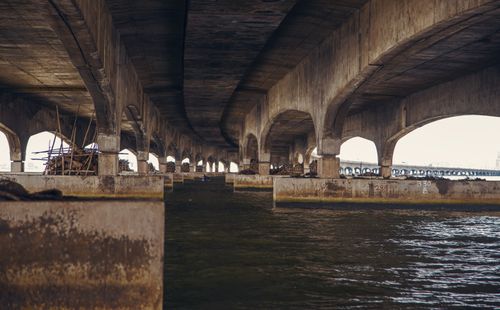 Free View under a vast concrete bridge with arches over a flowing river, showcasing architectural design. Stock Photo