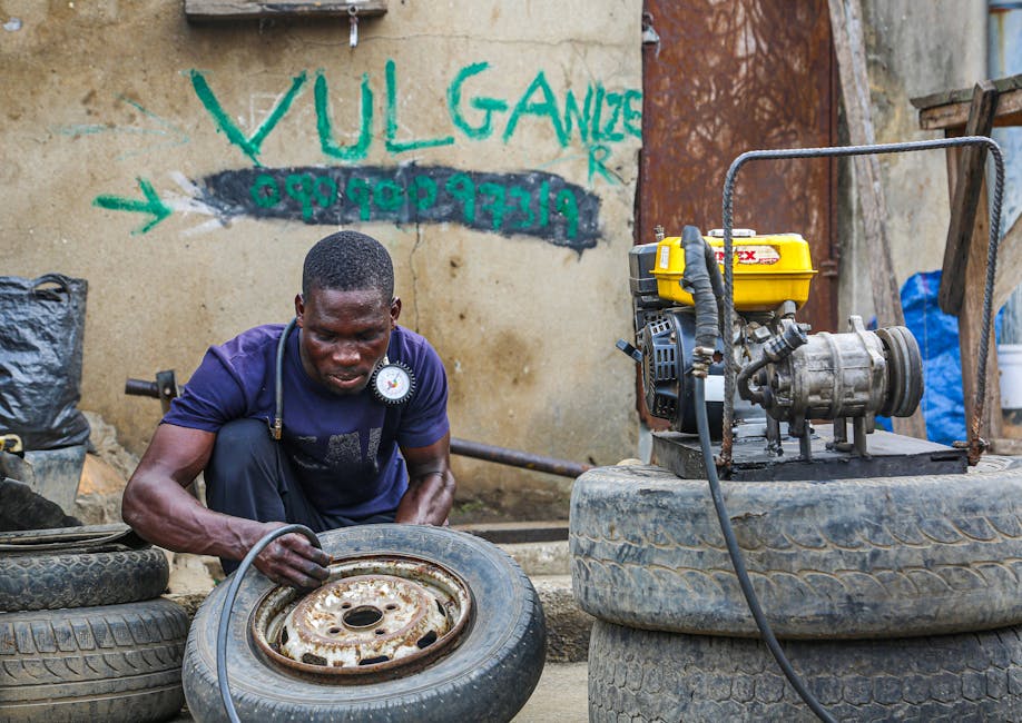 A mechanic vulcanizes a tire using equipment in an urban workshop setting.