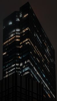 A striking modern skyscraper with illuminated windows against a dark night sky.