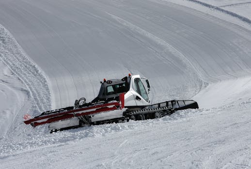A snow groomer preparing ski slopes on a bright winter day in the mountains.