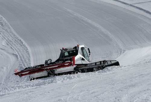 Free A snow groomer preparing ski slopes on a bright winter day in the mountains. Stock Photo