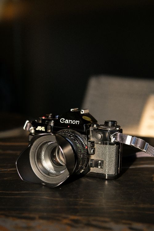Free Close-up shot of a vintage camera with lens on a wooden table, highlighted by natural light. Stock Photo