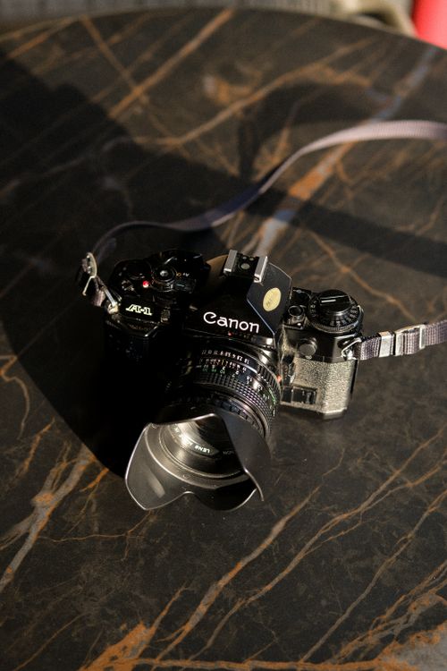 Free A vintage Canon film camera placed on a stylish marble table, capturing an artistic vibe. Stock Photo