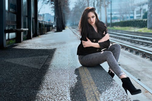 Woman in Black Coat Sitting Near the Train Track