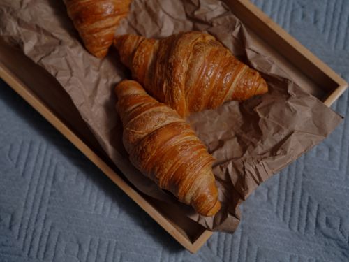 Free Delicious freshly baked croissants on a rustic wooden tray with brown paper lining. Stock Photo