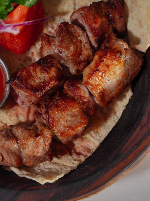 Free Appetizing grilled meat skewers served on flatbread with fresh tomato highlights Mediterranean flavors. Stock Photo