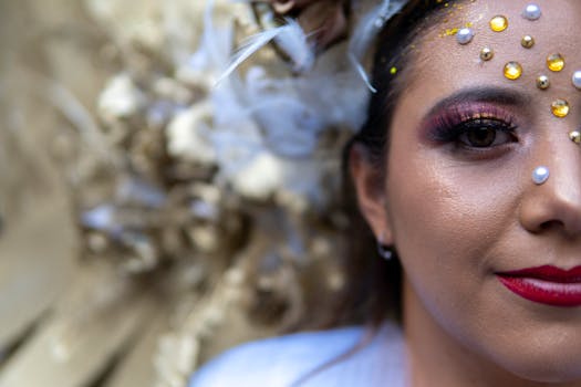 Close-up portrait of a woman with artistic makeup featuring gold accents and decorative jewels.