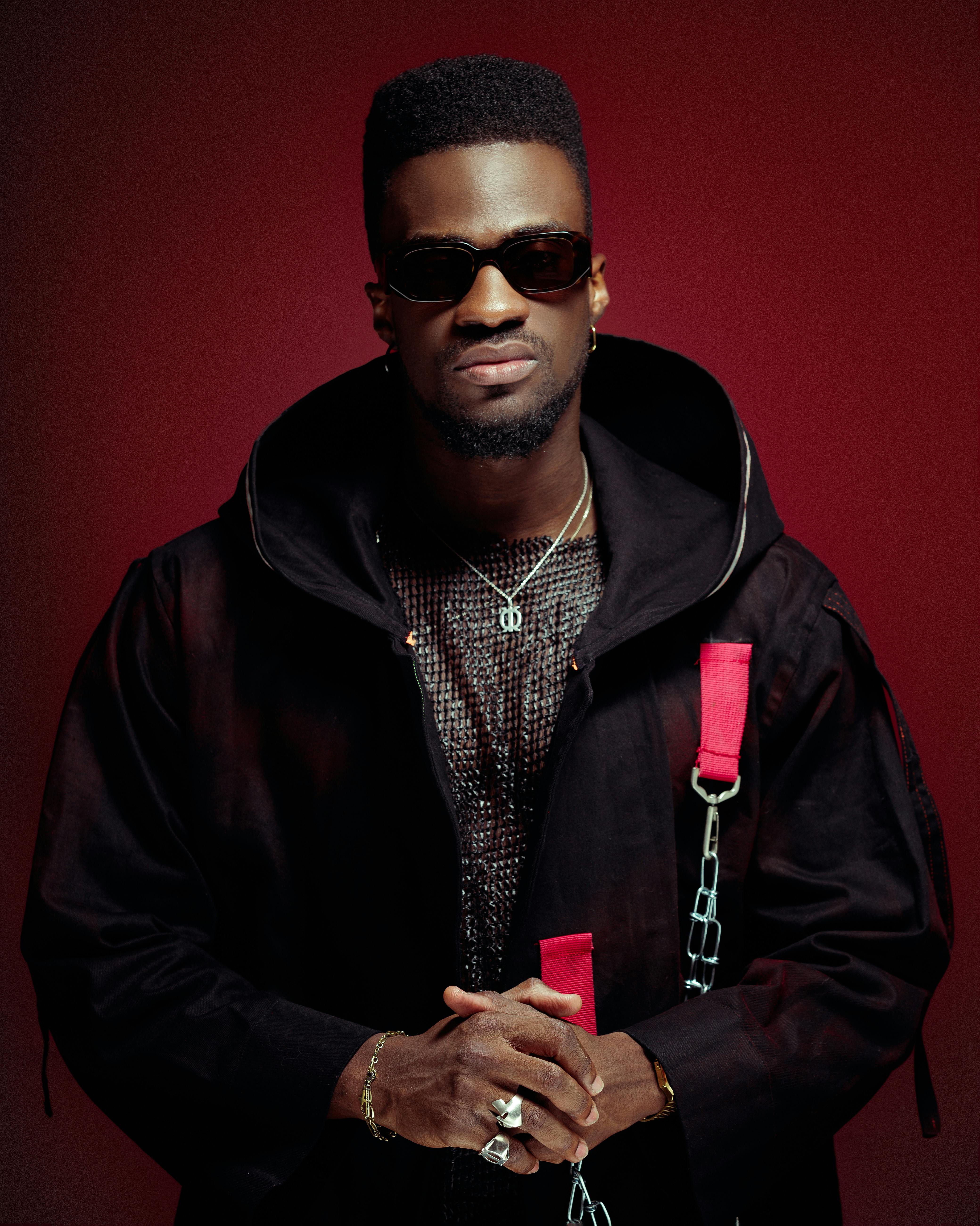 Confident African man modeling a trendy outfit with sunglasses in a studio setting.