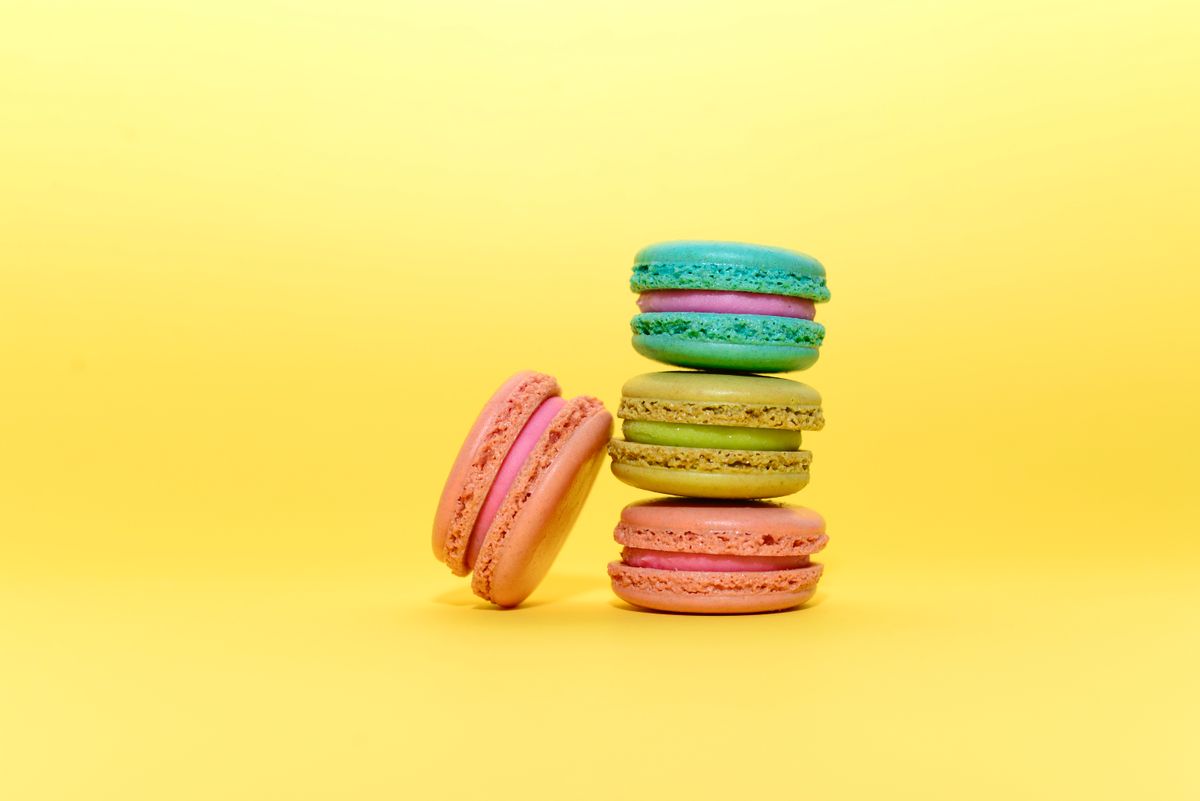 Colorful macarons displayed against a bright yellow background, perfect for sweets lovers.