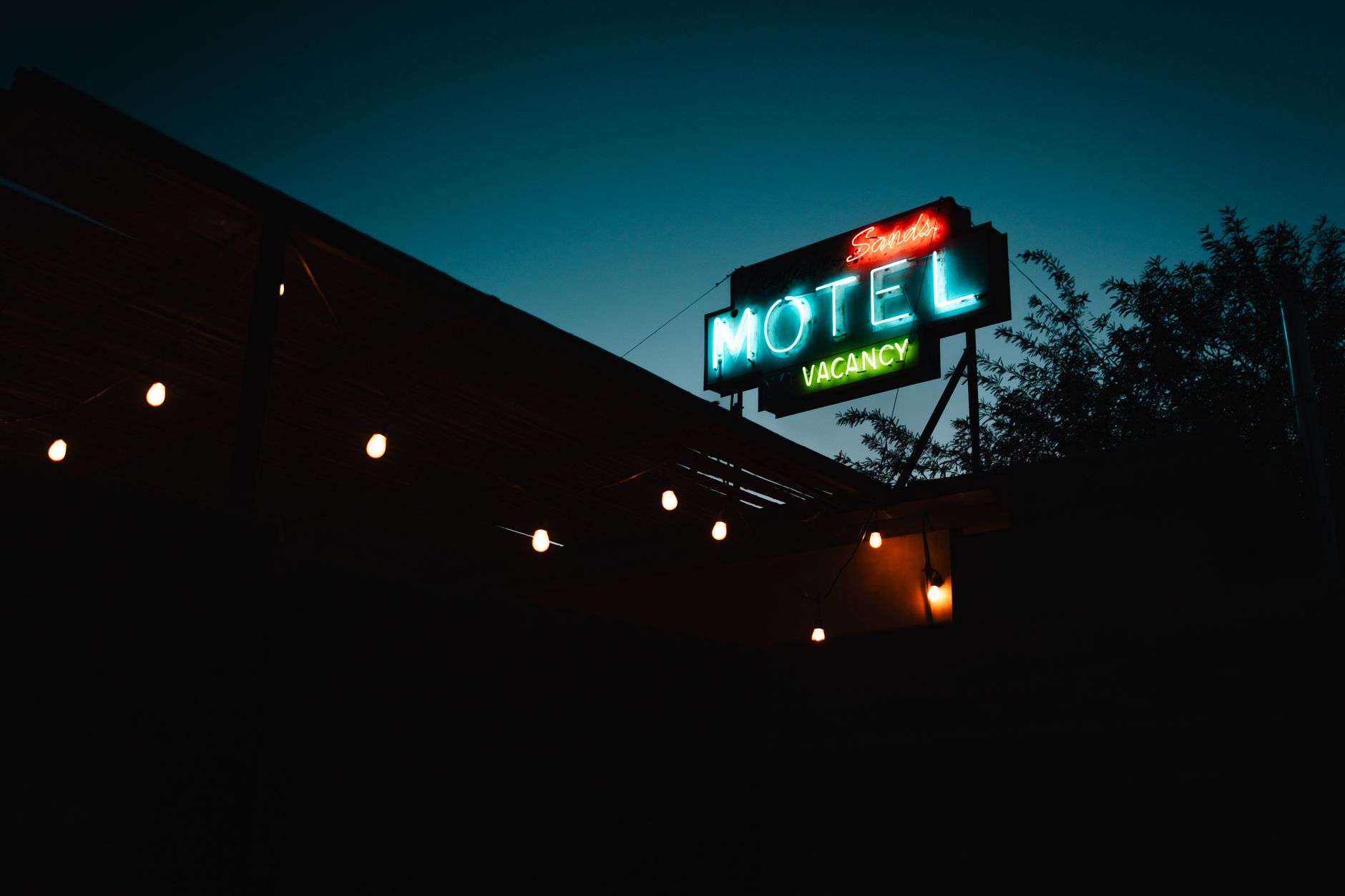 Atmospheric shot of a classic neon motel sign glowing in the evening light, indicating vacancy.