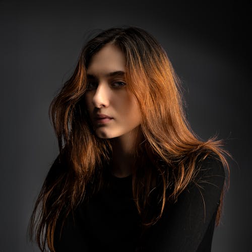 A woman with long red hair posing in black