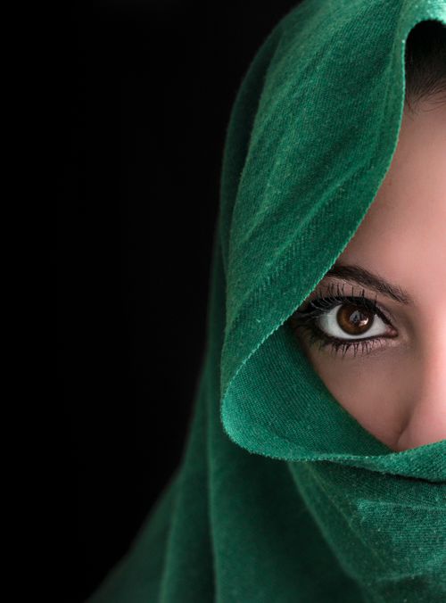 Free Close-up of a woman's eye partially covered by a green hijab against black background. Stock Photo