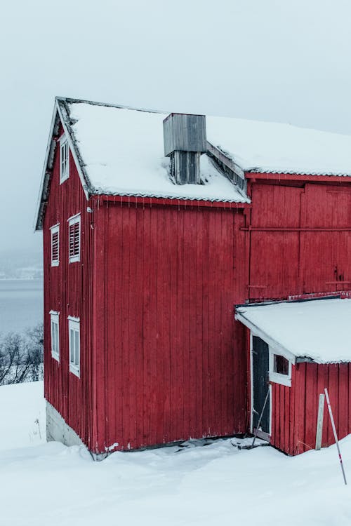 A red house in the snow with a snow covered roof