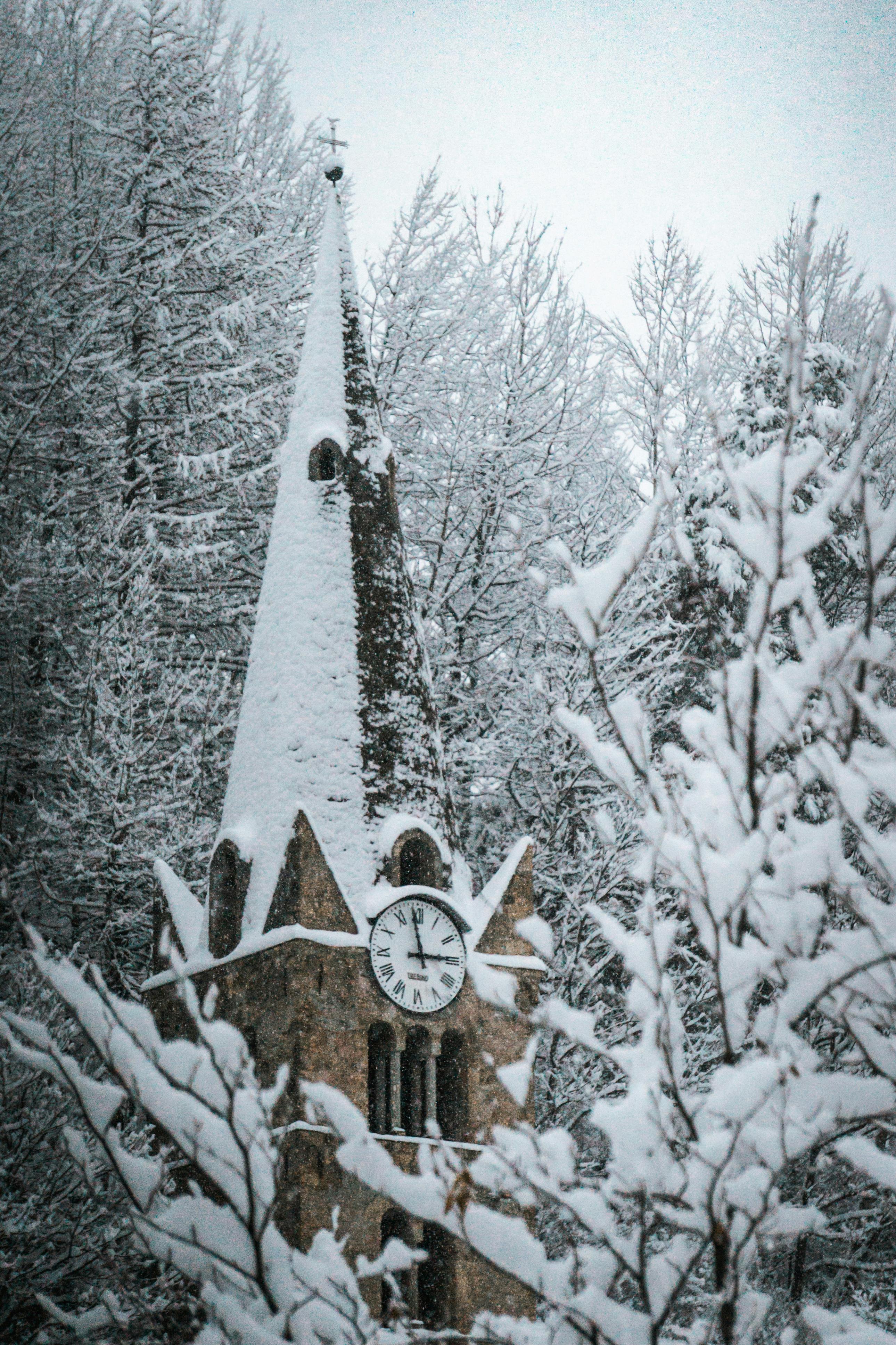 Snow-covered church tower in a serene winter forest setting, capturing a peaceful winter scene.