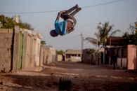 A young man performs a backflip in an urban street setting in Maputo, Mozambique.