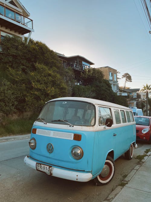 A blue and white vw bus parked on the side of the road