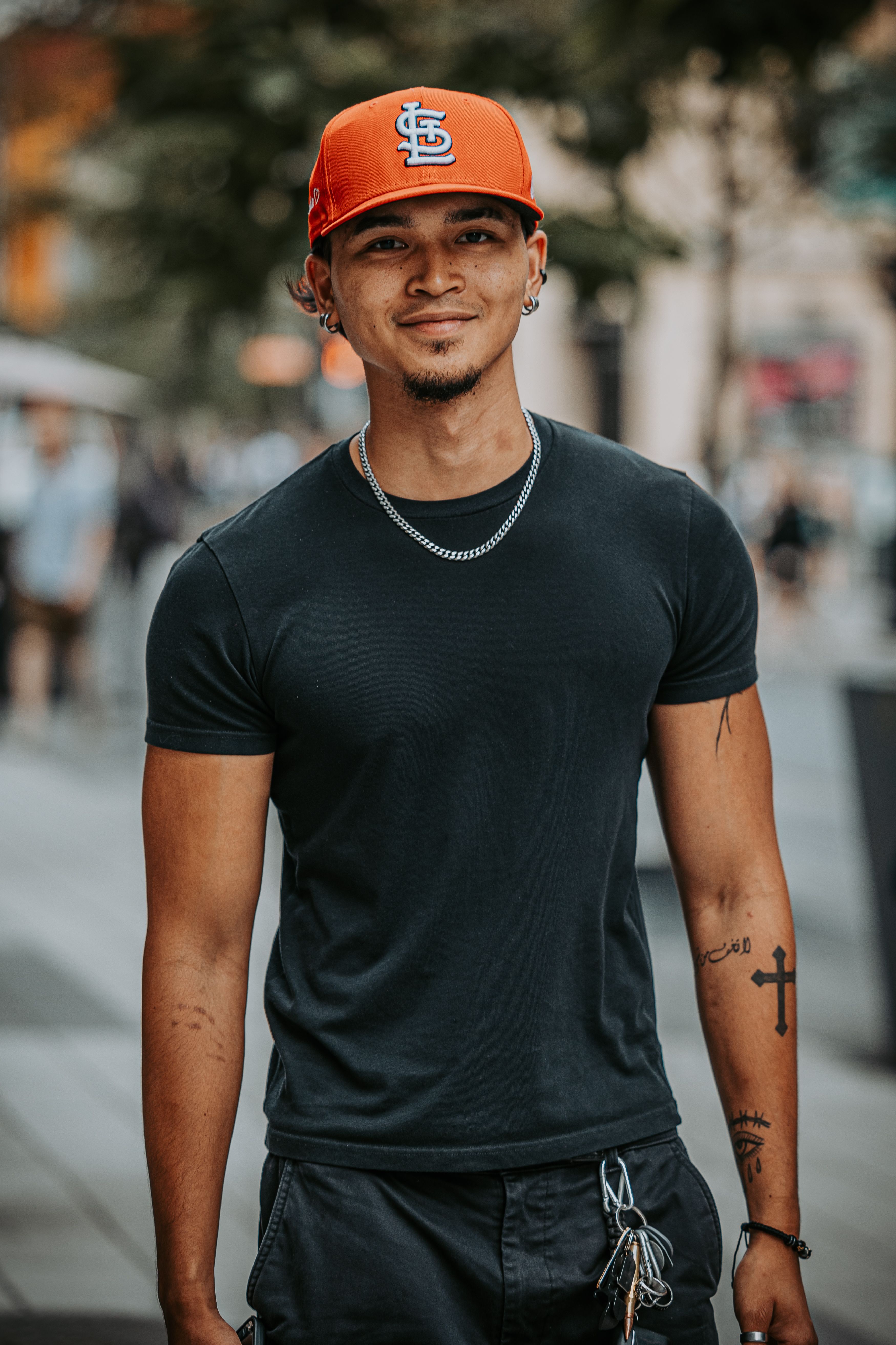 Confident man in a red cap and t-shirt smiling on a vibrant Montreal street.