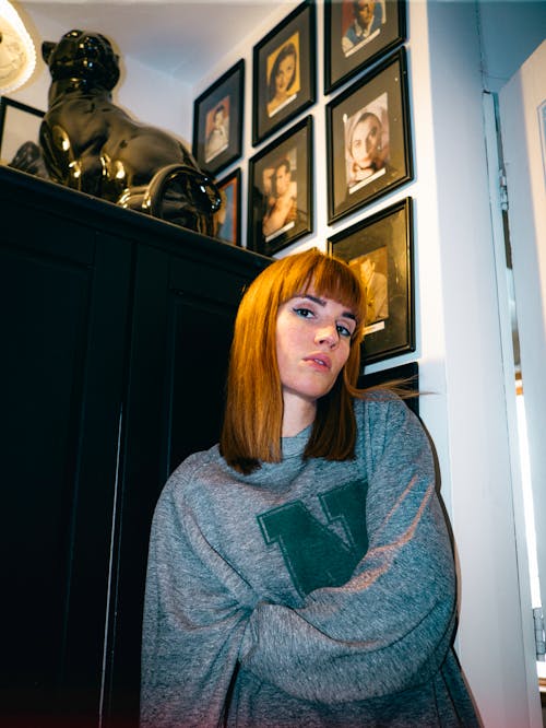 A woman with red hair and a grey sweatshirt