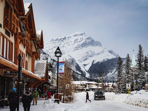 A snowy street with people walking and a mountain in the background