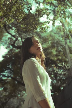 在自然光下拍摄的树林中，一名女子的肖像显得十分坦率