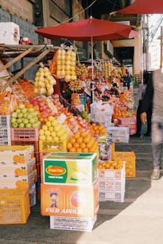 A lively street market with vibrant fruit displays and shoppers exploring the stalls.