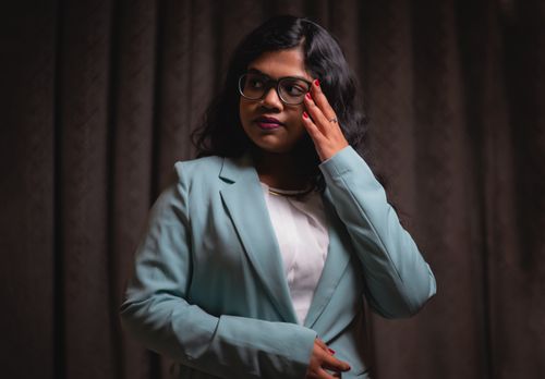 Free Stylish woman with eyeglasses in a blue blazer posing indoors, showcasing elegant fashion. Stock Photo