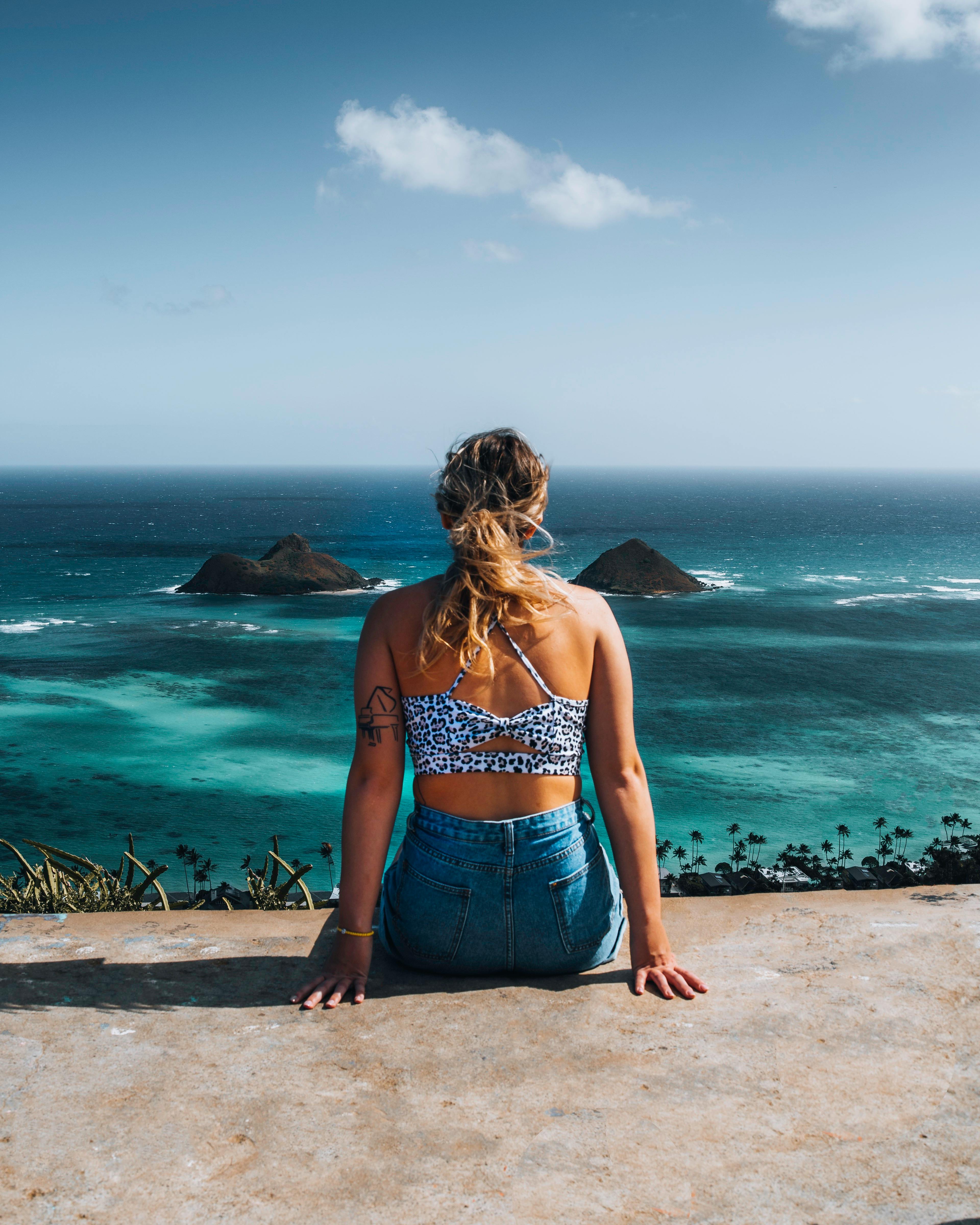Woman sitting with ocean view in Hawaii, embracing tropical vibes and tranquility.