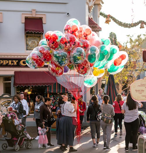 Woman Holding Balloons Surrounded by People at the Road