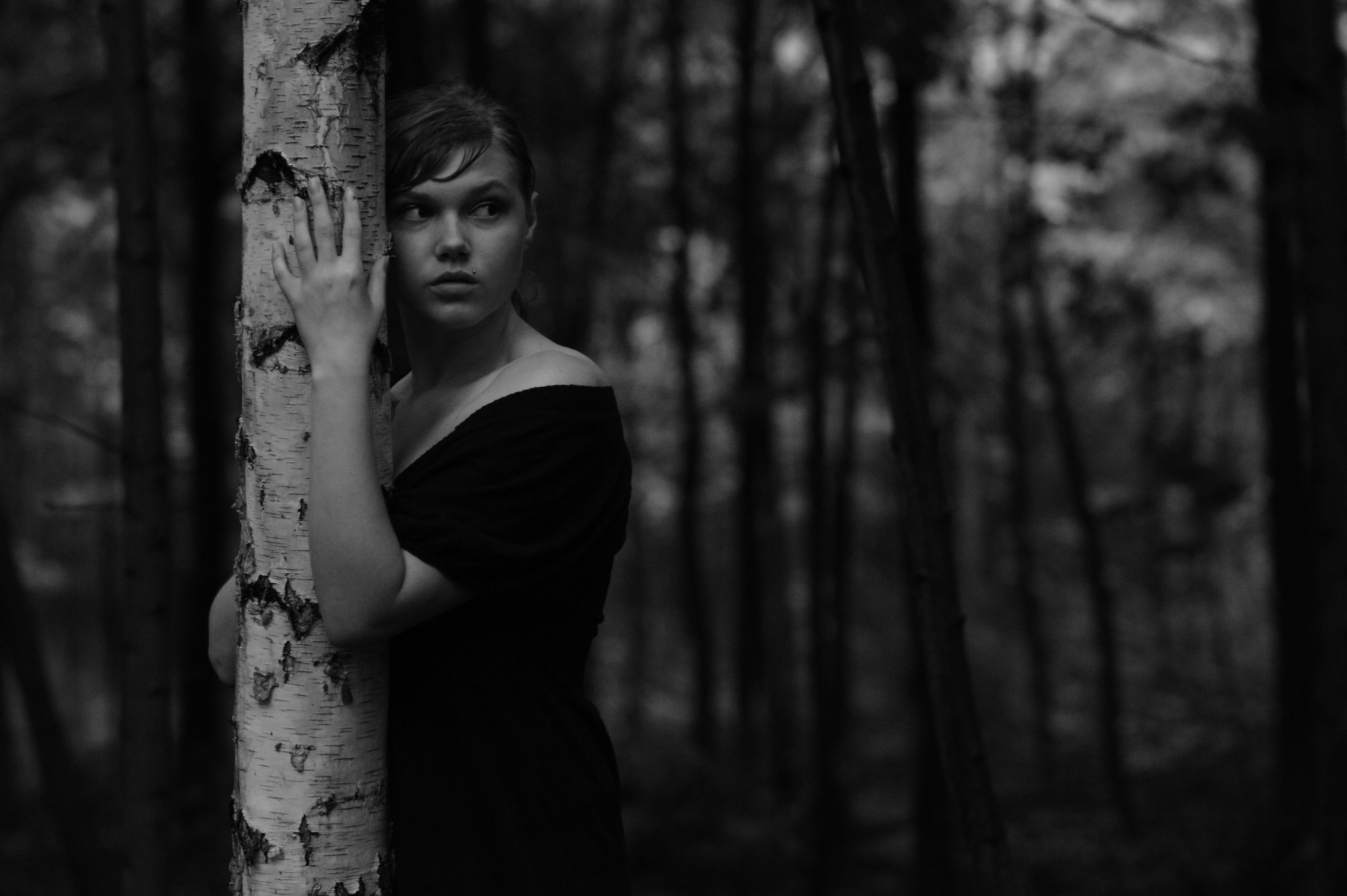 A woman is leaning against a tree in the woods · Free Stock Photo