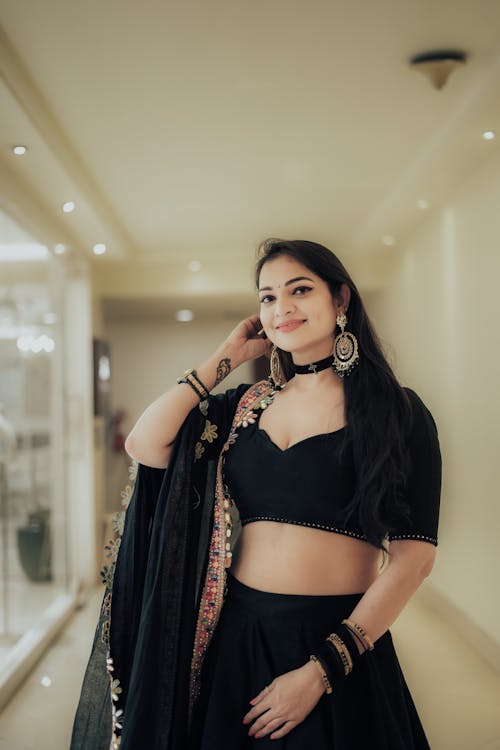 A woman in black lehenga and crop top posing for the camera