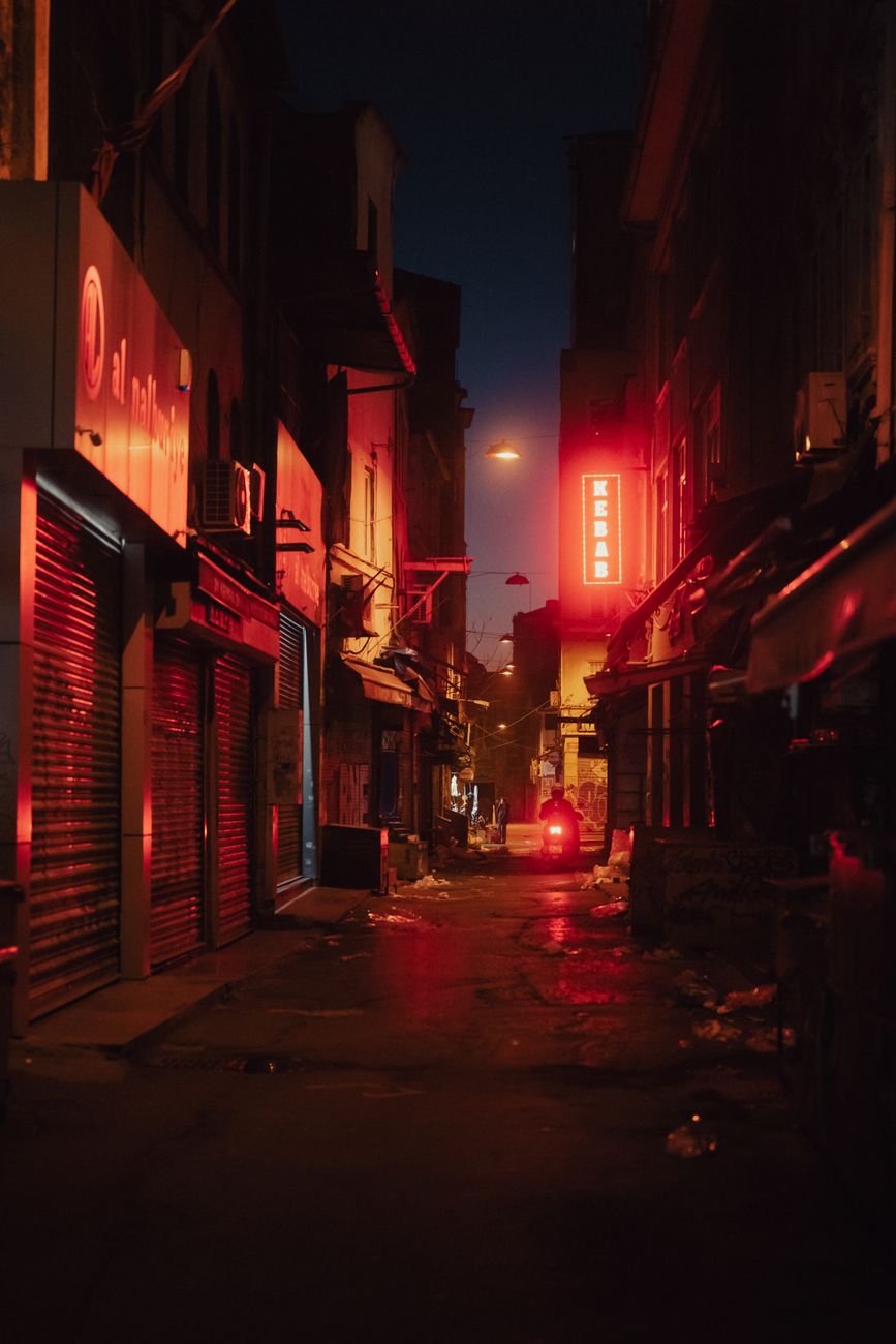 Explore the narrow, illuminated streets of Karakoy in Istanbul at night, with neon lights and a mysterious vibe.