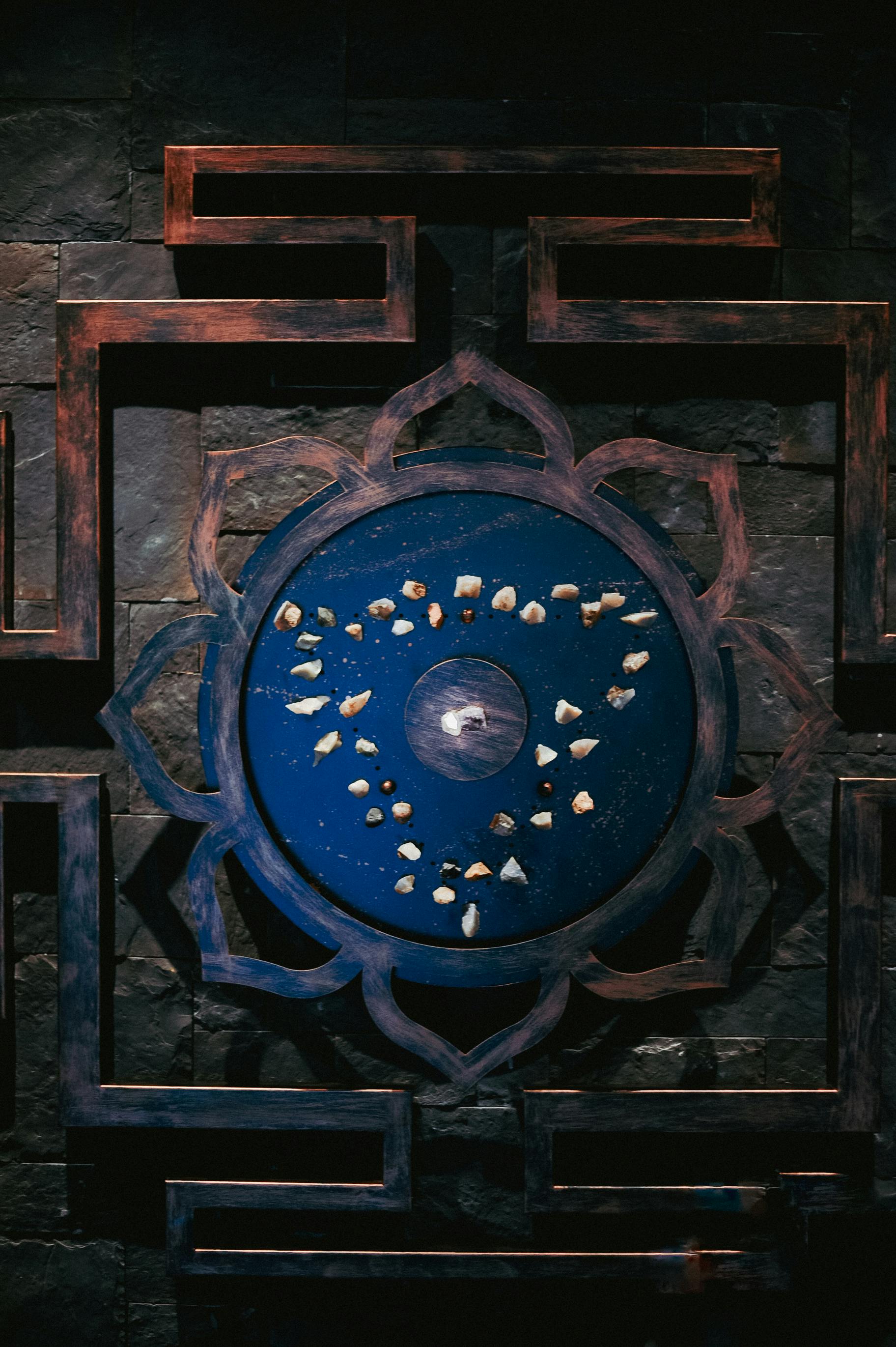 Intricate blue mandala with decorative stones on wooden background.